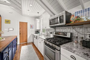 Une cuisine moderne avec des meubles blancs, une cuisinière en acier inoxydable, un four à micro-ondes et un plan de travail en granit.