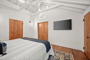 Une chambre à coucher avec un lit, des portes en bois, un téléviseur à écran plat et un tapis à motifs.