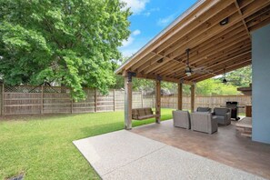 Un patio techado con techo de madera, asientos exteriores y una parrilla.
