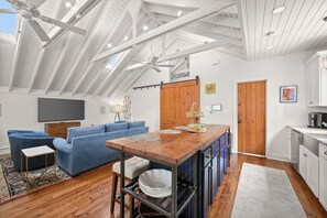 Une cuisine moderne avec un îlot central en bois, un canapé bleu et un ventilateur de plafond.