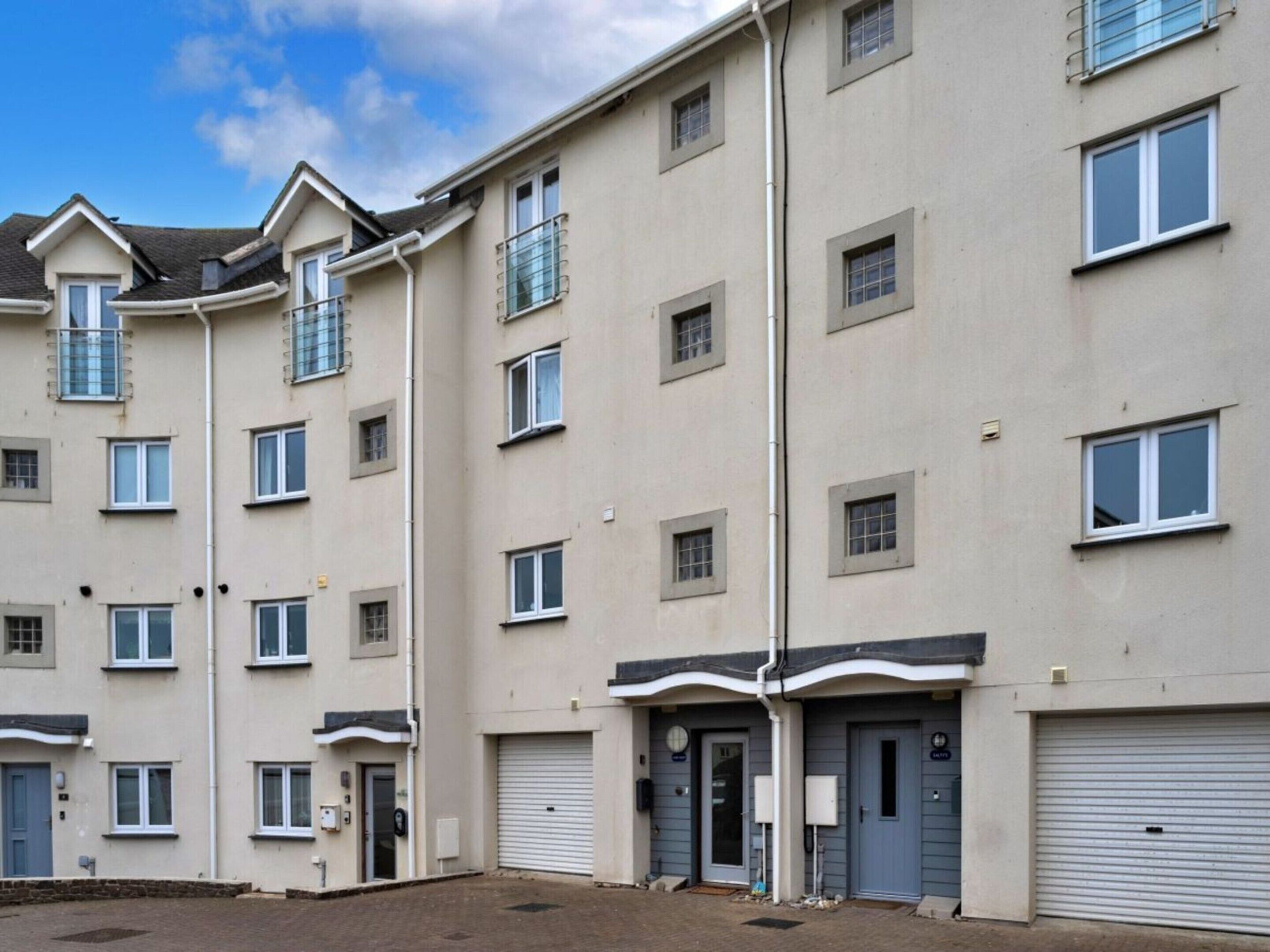 A multi-story residential building with a flat facade, multiple windows, and a gated entrance.