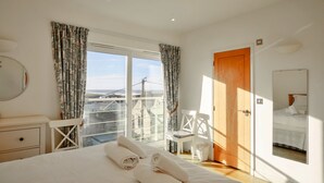 Ein Hotelzimmer mit einem Bett, einem Sessel, einer Holztür und Blick ins Freie.