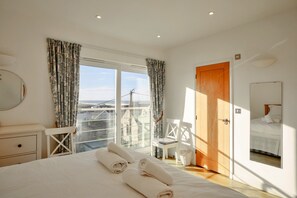 Ein Hotelzimmer mit einem Bett, einem Sessel, einer Holztür und Blick ins Freie.