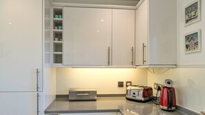 Eine Küche mit weißen Schränken, einem Toaster, einem Wasserkocher und einem kleinen Kühlschrank.