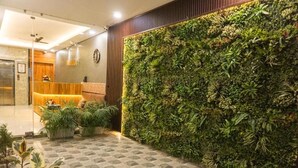 Un vestíbulo con mostrador de recepción, zona de estar y una pared con jardín vertical.