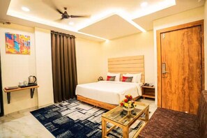 A hotel room with a bed, bedside table, and a ceiling fan. - The Havelock By EliteKeys (Indore)
