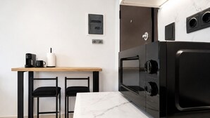 Een moderne keuken met een ingebouwde oven, een koffiezetapparaat en twee stoelen.