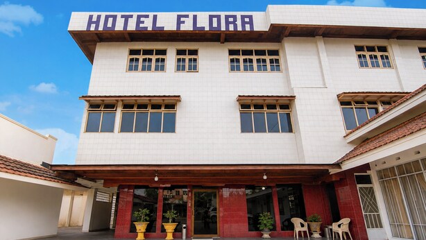 A two-story building with a sign reading 'HOTEL FLORA' at the top. There are multiple windows on each floor, and the entrance has a covered area with potted plants and outdoor seating. - Hotel O near RS Awal Bros Sudirman (Pekanbaru)