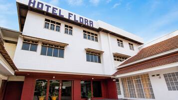 Et hotel med et tydeligt skilt, der siger 'HOTEL FLORA', flere vinduer og en fliset indgang.