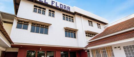 A hotel with a prominent 'HOTEL FLORA' sign, multiple windows, and a tiled entrance.