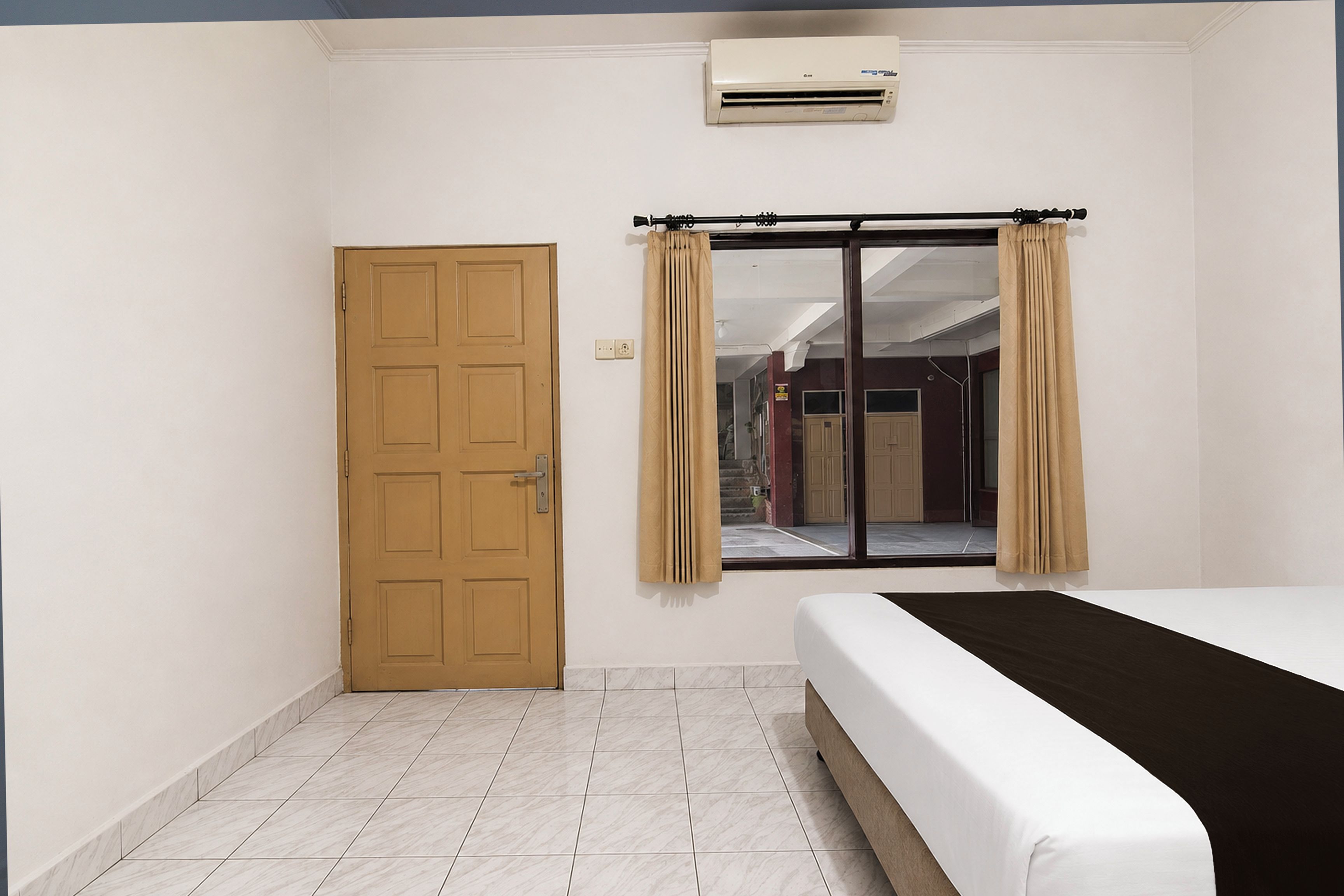 A room with a bed, a door, and a window with curtains.