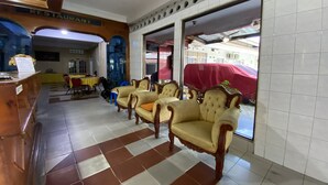 Una hall d'albergo con reception, sala da pranzo e area salotto con poltrone imbottite.
