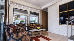 A lobby with ornate sofas, a coffee table, and a view through large windows. - Hotel O near RS Awal Bros Sudirman (Pekanbaru)