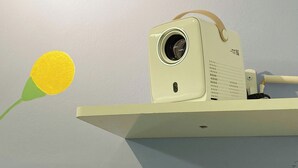 Een beamer op een witte standaard met een beige band.