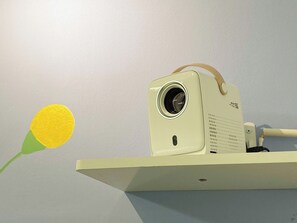 Ein Projektor auf einem weißen Ständer mit einem beige-farbenen Trageriemen.