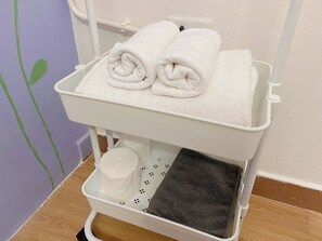 Ein weißer, mobiler Toilettenwagen mit Handtuchhalter und Mülleimer.