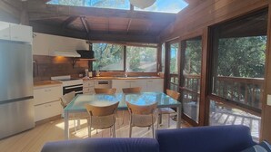 A modern kitchen with a dining area, large windows, and a ceiling skylight.