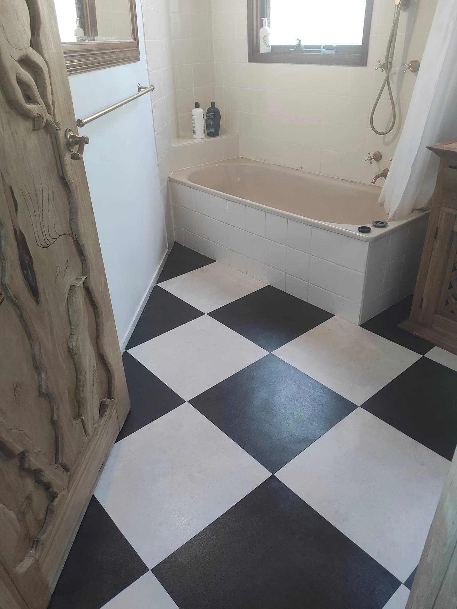 A bathroom with a checkered floor, a bathtub, and a window.