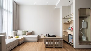 Una sala de estar moderna con un sofá modular, una mesa de centro de madera y un pequeño comedor.