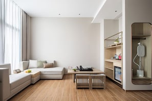 A modern living room with a sectional sofa, a wooden coffee table, and a small dining area. - Shenzhen Nanshan Ruijing Hotel (Shenzhen)