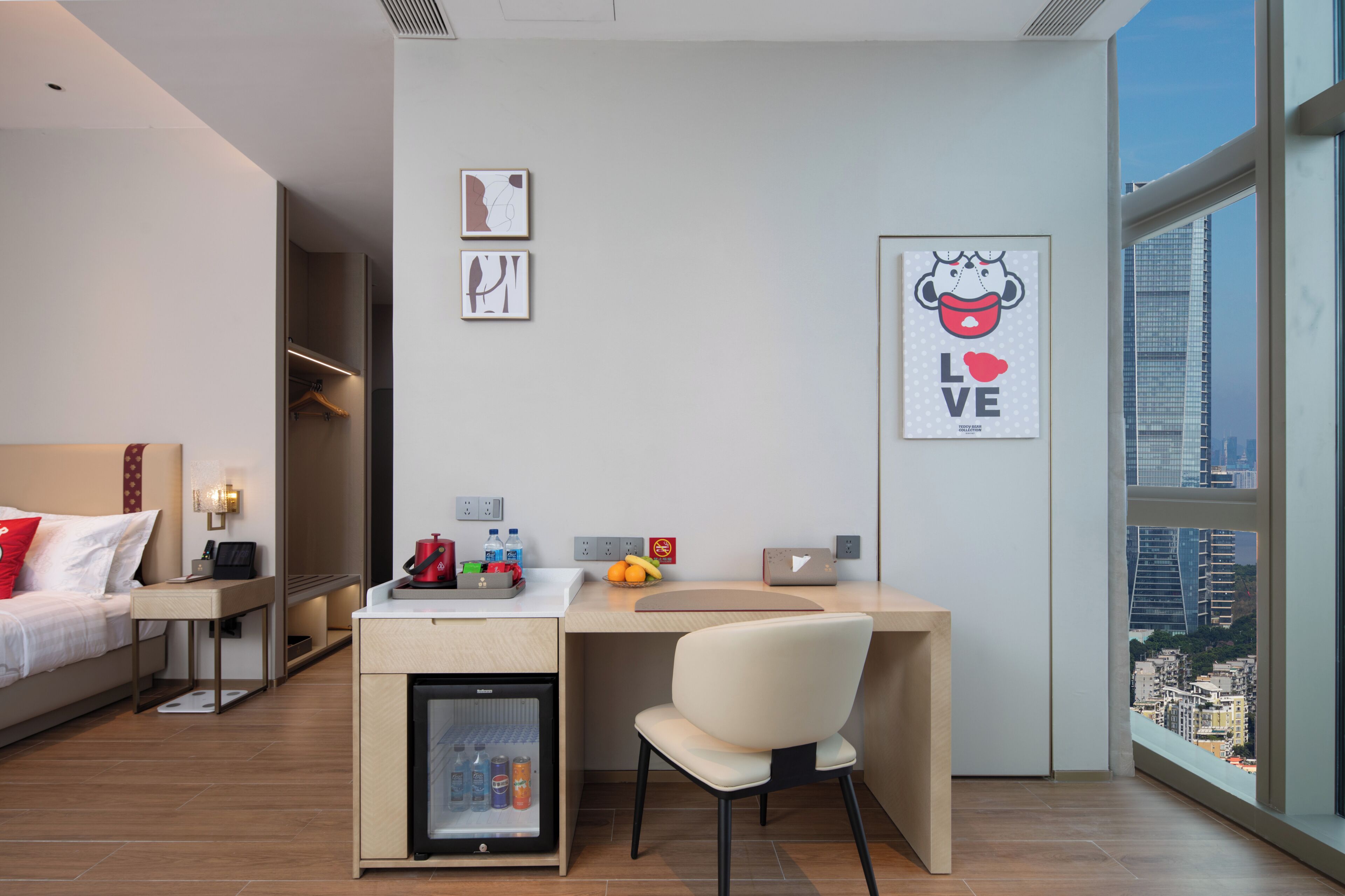 Una habitación de hotel moderna con una cama, un escritorio con una silla, un mini refrigerador y obras de arte en las paredes.