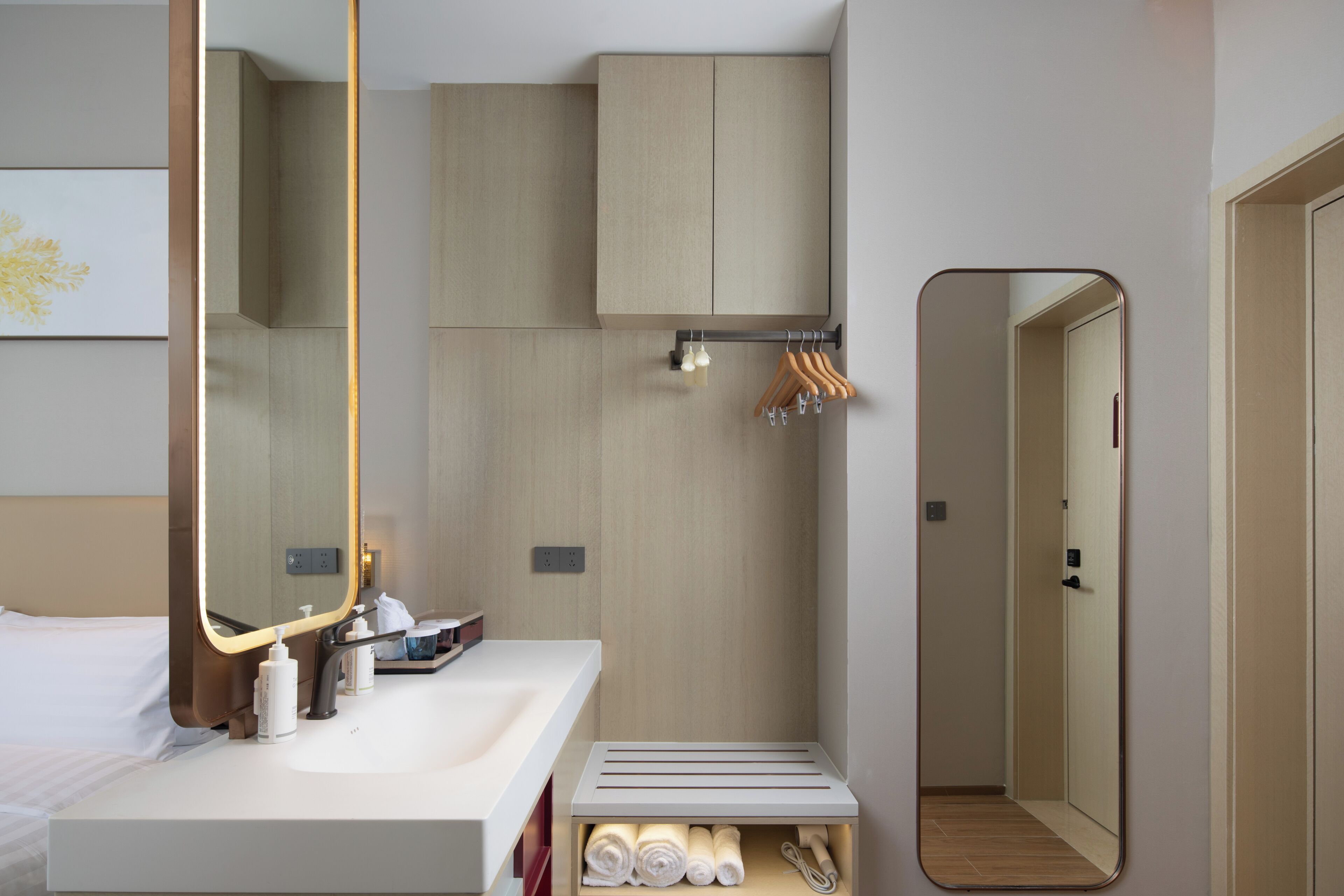 A modern hotel bathroom with a large mirror, a sink, and a towel rack.