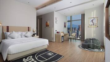 Une chambre d’hôtel avec un lit, un bureau, une chaise, un canapé et une vue sur la ville.