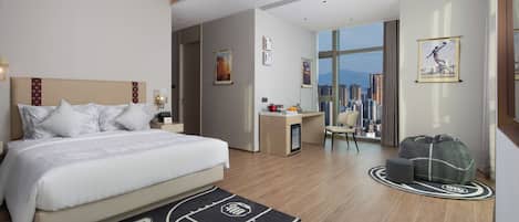 Una habitación de hotel con cama, escritorio, silla, sofá y vistas a la ciudad.