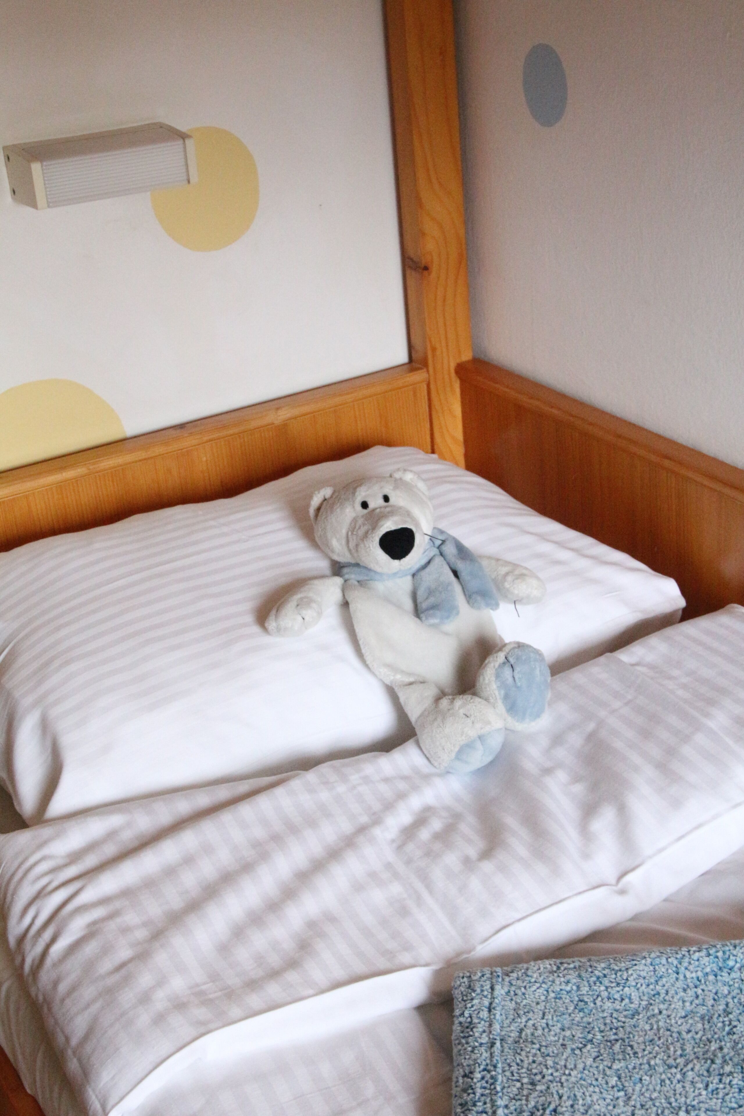 Un lit avec un matelas blanc et un ours en peluche dessus.