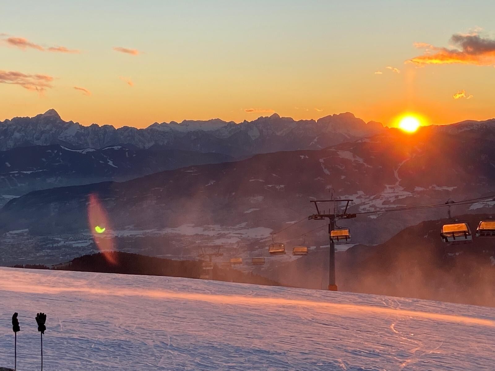 A ski slope with a ski lift and mountains in the background.