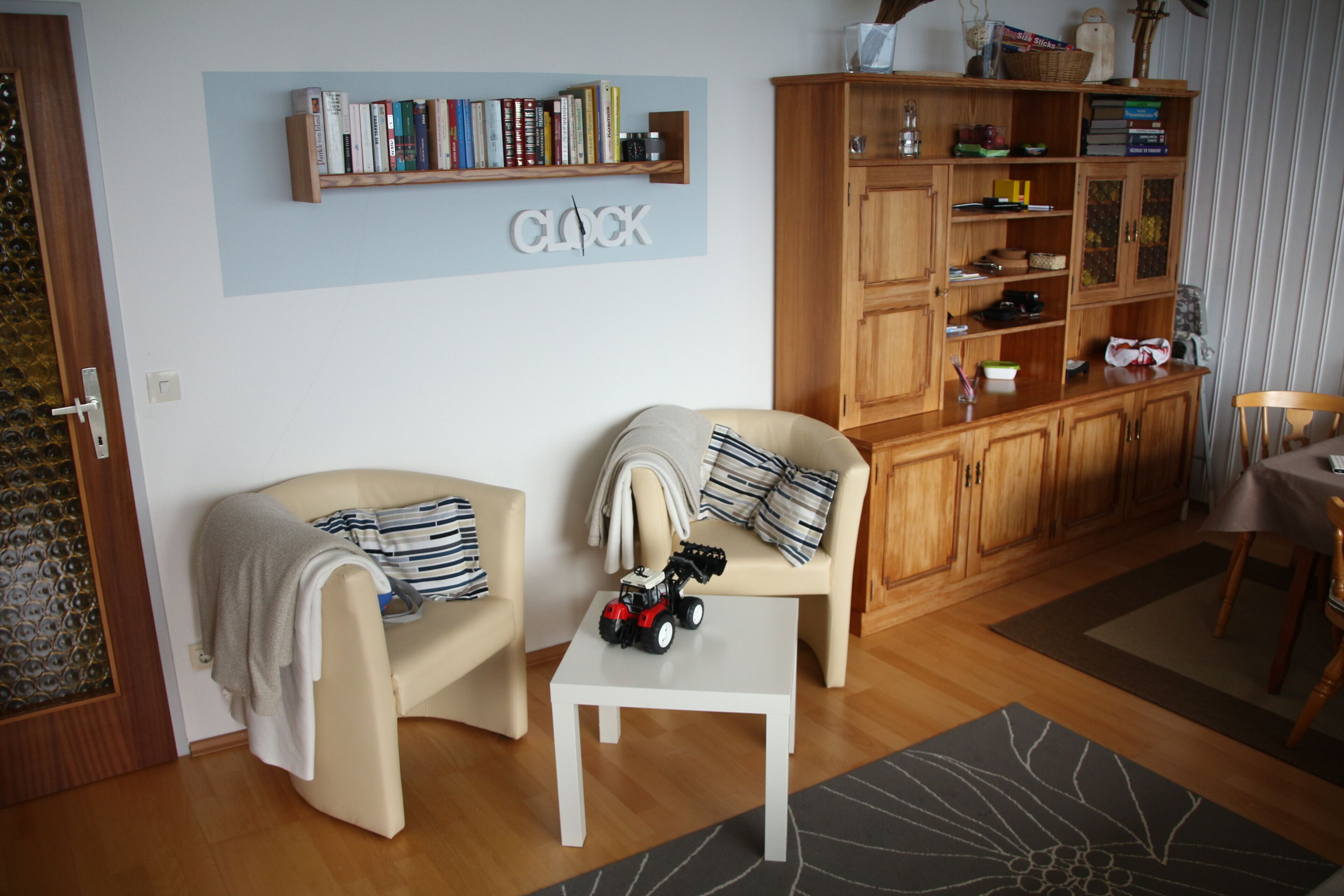 Un salon comprenant deux fauteuils, une table basse, une bibliothèque et un coin repas.