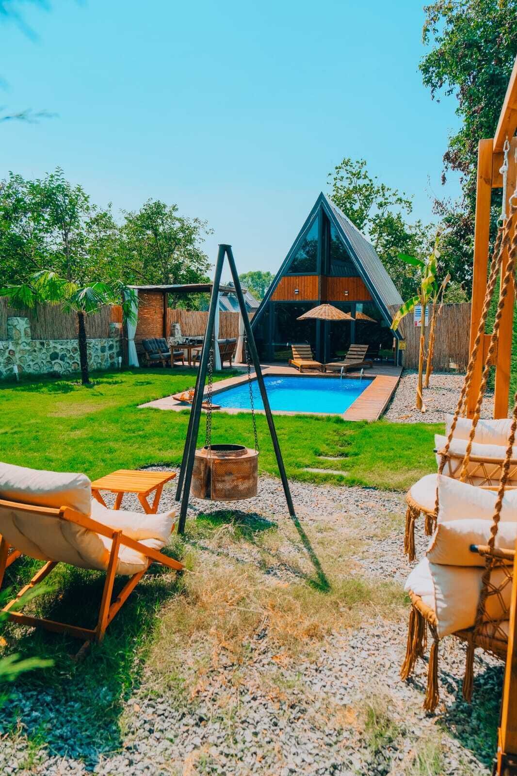 A modern outdoor pool area with a swing set, lounge chairs, and a wooden deck.