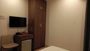 A bedroom with a bed, a television mounted on the wall, a small desk with a chair, and a wardrobe. - Kingston Home (Nha Trang)