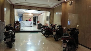 A hotel lobby with a reception desk, a 'Welcome' mat, and several parked scooters. - Kingston Home (Nha Trang)