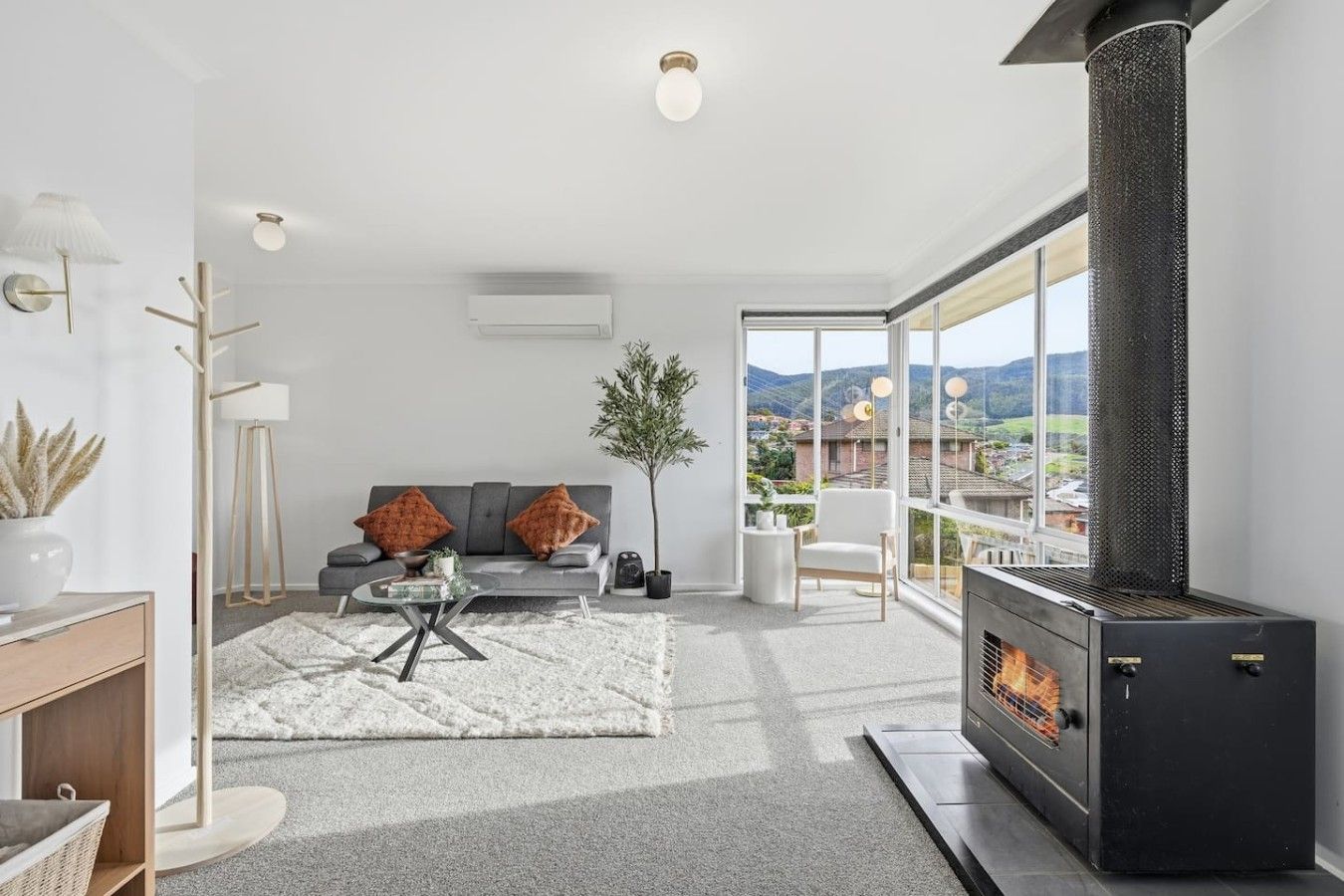 Una sala de estar moderna con chimenea, un sofá con cojines, una mesa de centro y vistas al exterior.