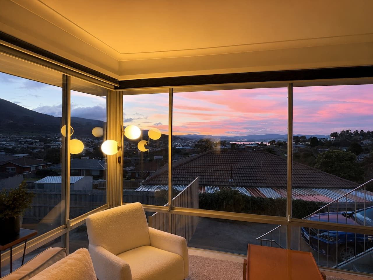 Una habitación con un ventanal grande, una silla y una mesita.