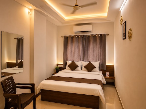 A hotel room with a bed, a chair, a ceiling fan, an air conditioning unit, and a wall-mounted mirror. - Hotel The One (Rajkot)