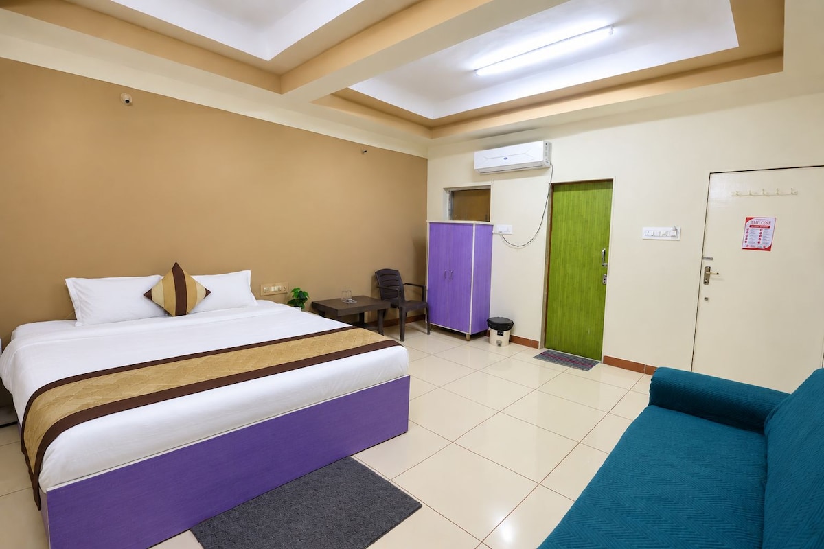 A hotel room with a bed, a desk, a chair, a wardrobe, and a green door.
