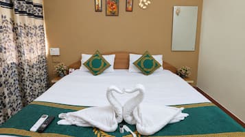 A hotel room with a bed, pillows, a remote control, and a decorative towel arrangement.