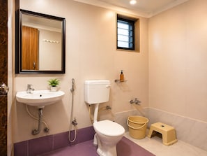 A bathroom with a sink, toilet, shower, and a small window. - Hotel The One (Rajkot)