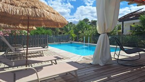 A wooden deck with a pool, lounge chairs, and a thatched umbrella. - Private studio Guesthouse Casa Dani Portugal 3 persons nearby Tomar (Santarém)