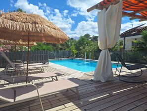 A wooden deck with a pool, lounge chairs, and a thatched umbrella. - Private studio Guesthouse Casa Dani Portugal 3 persons nearby Tomar (Santarém)