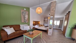 A modern living room with a herringbone floor, a brown sofa, a wooden coffee table, and a large painting on the wall. - Private studio Guesthouse Casa Dani Portugal 3 persons nearby Tomar (Santarém)
