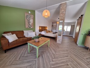 A modern living room with a herringbone floor, a brown sofa, a wooden coffee table, and a large painting on the wall. - Private studio Guesthouse Casa Dani Portugal 3 persons nearby Tomar (Santarém)