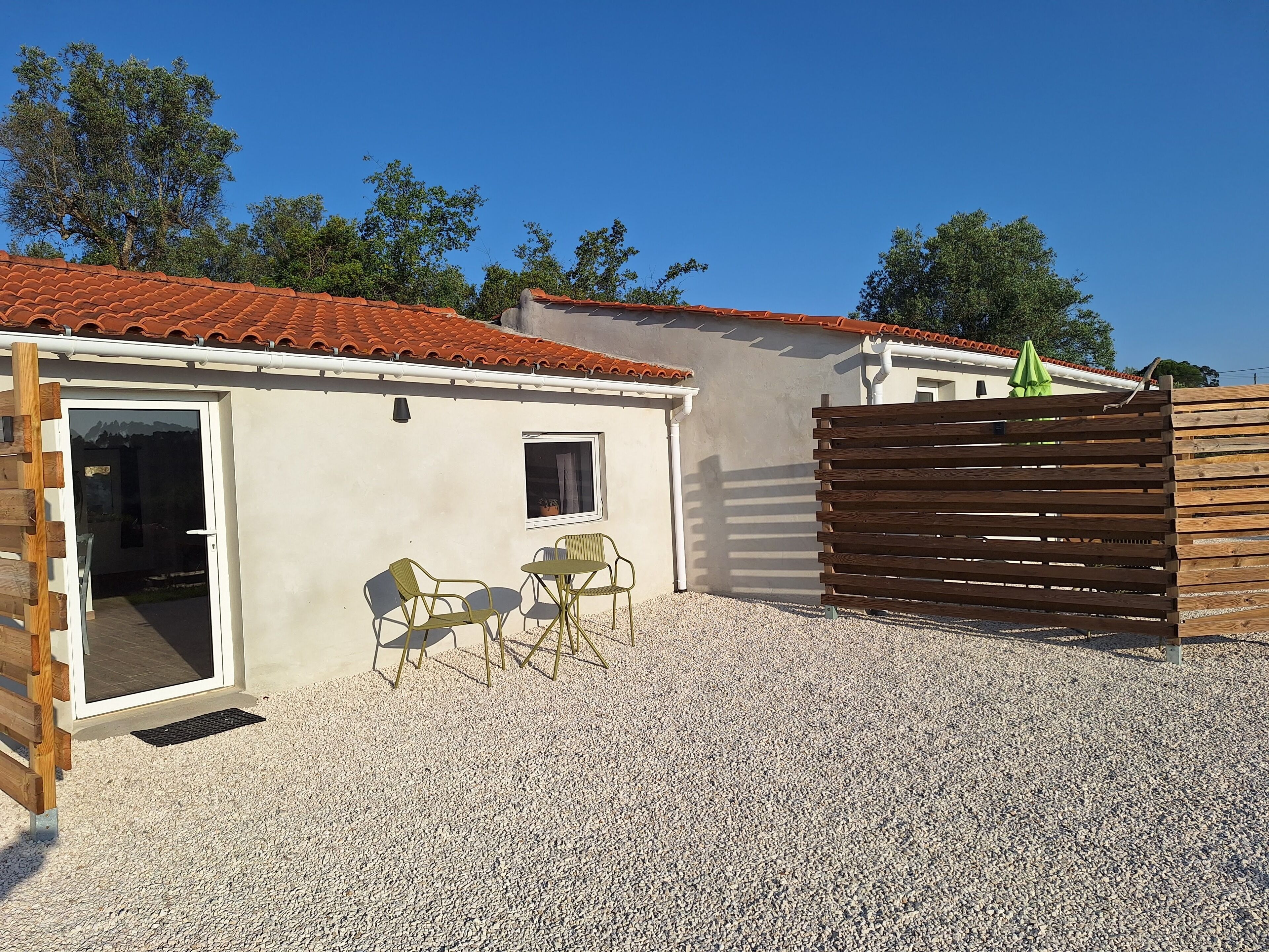 A building with a tiled roof, a wooden fence, and a gravel driveway.