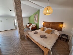 A spacious bedroom with a large bed, a wooden headboard, and a hanging light fixture. - Private studio Guesthouse Casa Dani Portugal 3 persons nearby Tomar (Santarém)