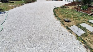 A gravel driveway leading to a white building with a solar panel roof, surrounded by greenery and a clear blue sky. - Private studio Guesthouse Casa Dani Portugal 3 persons nearby Tomar (Santarém)