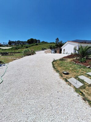 A gravel driveway leading to a white building with a solar panel roof, surrounded by greenery and a clear blue sky. - Private studio Guesthouse Casa Dani Portugal 3 persons nearby Tomar (Santarém)