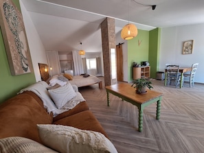 A modern living room with a sofa, a wooden coffee table, and a dining area with chairs. - Private studio Guesthouse Casa Dani Portugal 3 persons nearby Tomar (Santarém)