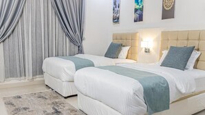 Una camera d'albergo con due letti, un'ampia finestra con tende, un comodino con una lampada e opere d'arte appese al muro.